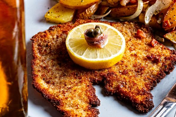 Wienerschnitzel with a lemon wheel, capers, and anchovy