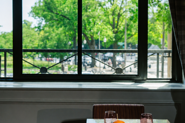 A dining table overlooking views of the Washington Monument through expansive windows at Fireclay, featuring a plated burger and fries in a bright, light-filled setting.
