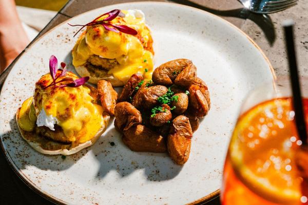 Eggs benedict breakfast dish made with poached eggs, hollandaise, and served on an English muffin