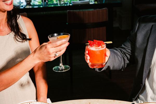 two people cheersing cocktails