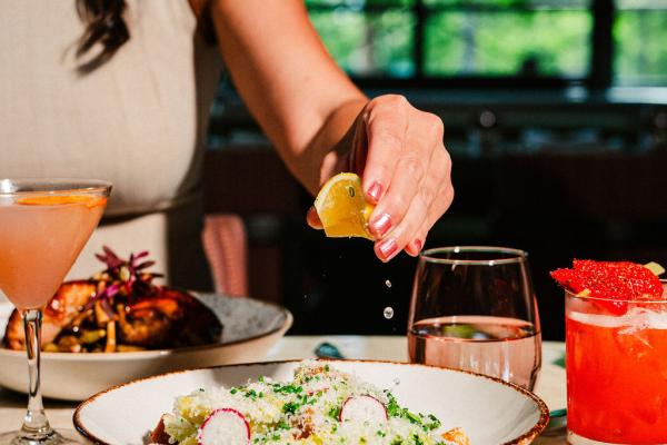 woman squeezing fresh lemon slice over the top of a Caesar salad