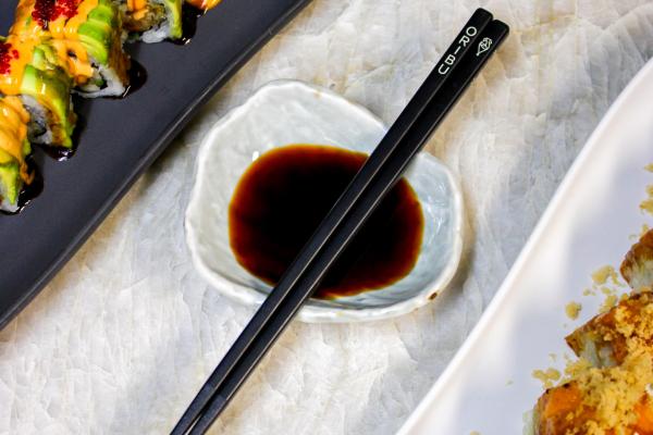 two sushi dishes with chop sticks and soy sauce in the middle