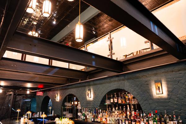 An overhead view down through District Still's multi-level space, with large Art Deco pendant lanterns and guests gathered at the bar below.