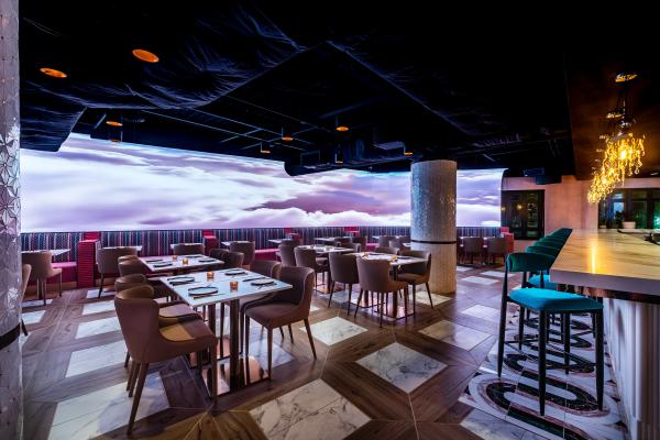Wide shot of light room with cloud imagery on screen